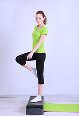 Beautiful young woman exercises on stepper