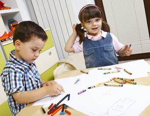 A boy and a girl learning to draw with crayons