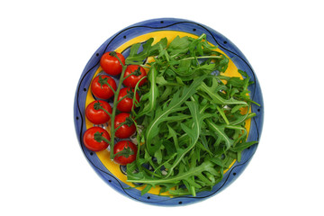 Arugula leaves and cherry tomatoes on vintage plate on white