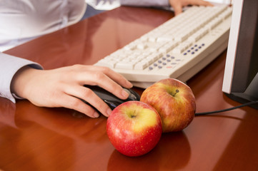 Human hands working on a computer  and two apples to eat