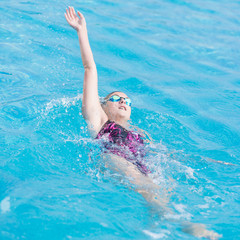 Woman in goggles swimming back crawl style