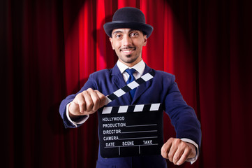 Man with movie clapper on curtain background