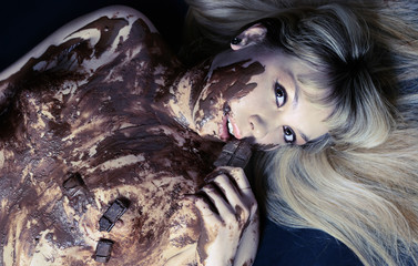 The girl covered with hot chocolate lies on a black background