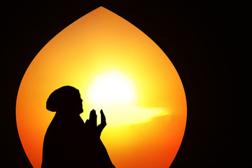 Beautiful orange silhouette of muslim praying at mosque