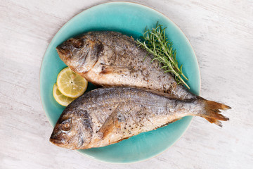 Grilled sea bream on plate, top view.