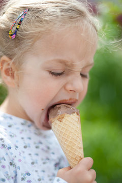 Kleines blondes M&auml;dchen schleckt Eis