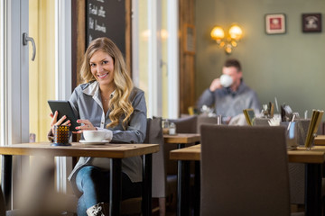 Pregnant Woman Using Digital Tablet In Coffeeshop