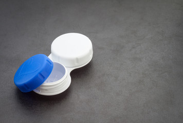 Open contact lens case on dark background.