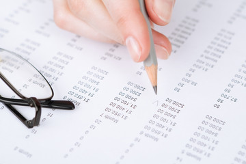 Obraz premium Close up of hand making notes in the document with pencil