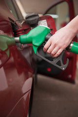 Woman refilling red car with green fuel