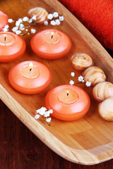 Beautiful candles in water on wooden table close-up