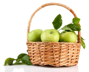 Juicy green apples with leaves in basket, isolated on white