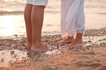 legs of kissing couple on beach