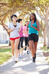 Group Of Female Runners Exercising On Suburban Street