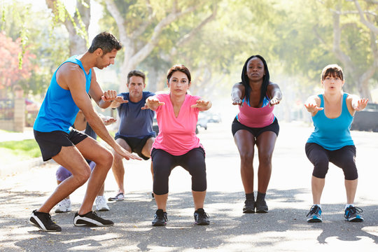 Group Of People Exercising Street With Personal Trainer
