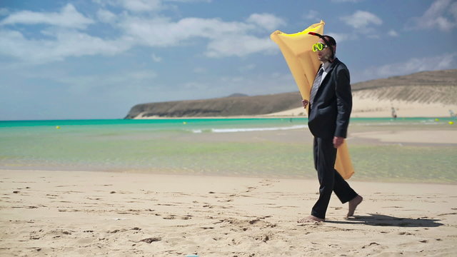 Businessman walking on the beach with inflatable mattress and we