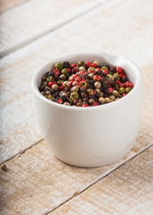 Mixed pepper in white bowl on wooden background