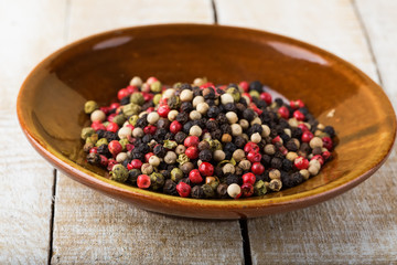 Mixed pepper on plate  on wooden background