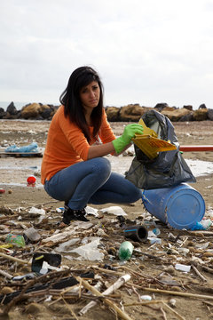 Young social worker cleaning dirty beach