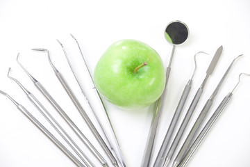 Green apple and dental tools isolated on white