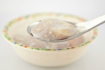 Banana in coconut milk on metal spoon show Thai dessert