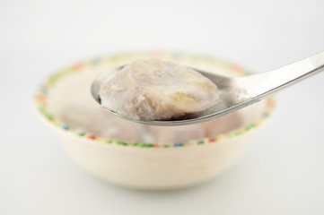 Banana in coconut milk on metal spoon show Thai dessert