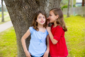 kid friend girls whispering ear playing in a park tree