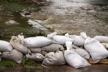 Sandsäcke als Hochwasserschutz auf überfluteter Straße nach Starkregen