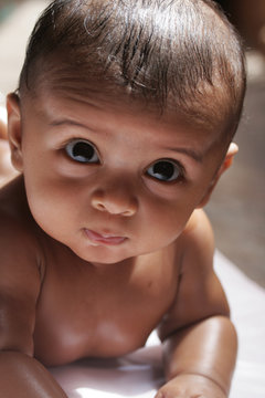 A close up image of a Small Male Baby with Big eyes looking