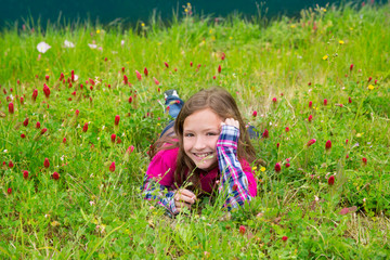 Happy relaxed kid girl on a spring flowers meadow