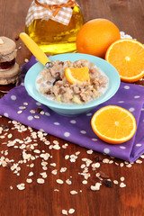 Useful oatmeal in bowl with fruit on wooden table close-up