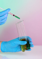 Hands in gloves and test tubes on blue-purple background