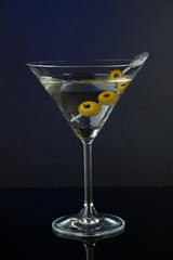 Martini glass with olives on dark blue background