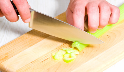 Chef cutting the celery on a wooden board