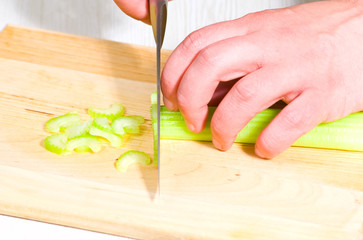 Chef cutting the celery on a wooden board