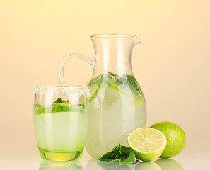 Lemonade in pitcher and glass on yellow background