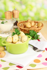 Tender young potatoes with sour cream and herbs in pan