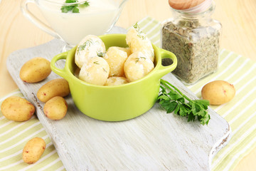Tender young potatoes with sour cream and herbs in pan