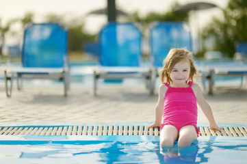 Adorable little girl sitting by a swimming pool © MNStudio