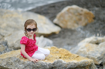 Adorable little girl sitting on a rock