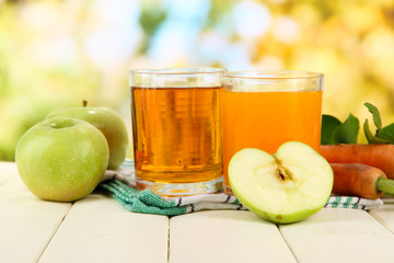 Glasses of juice, apples and carrots
