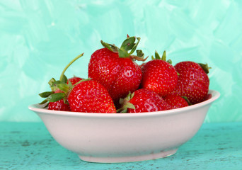 Strawberries in plate on blue background