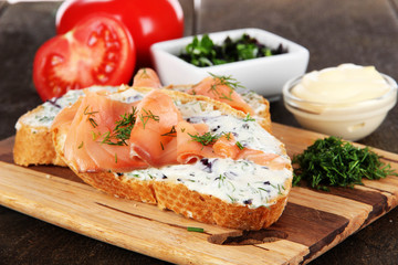 Fish sandwiches on cutting board on wooden table