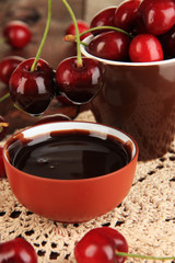 Ripe red cherry berries in cup and chocolate sauce