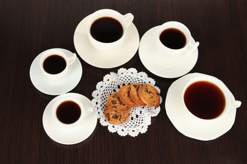 Cups of coffee and cookies on napkin on dark background