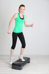 Fototapeta na wymiar Beautiful young woman exercises on stepper