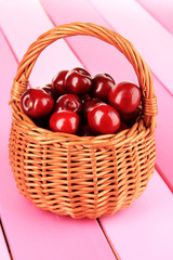 Cherry berries in wicker basket on wooden table close-up