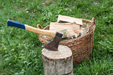 An axe stuck in a log in front of basket with logs fire