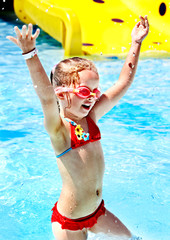 Child with armbands playing in swimming pool.