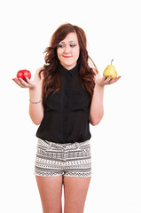 Young woman comparing an apple and a pear, trying to decide whic